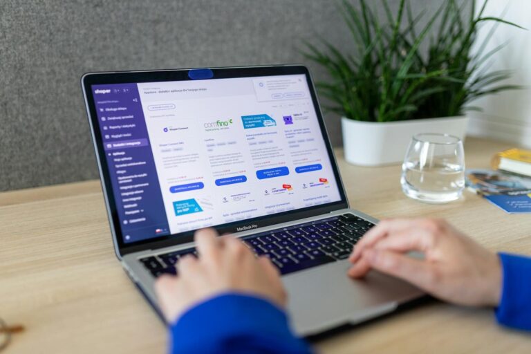 Close-up of hands on a laptop browsing an e-commerce site in a modern office.
